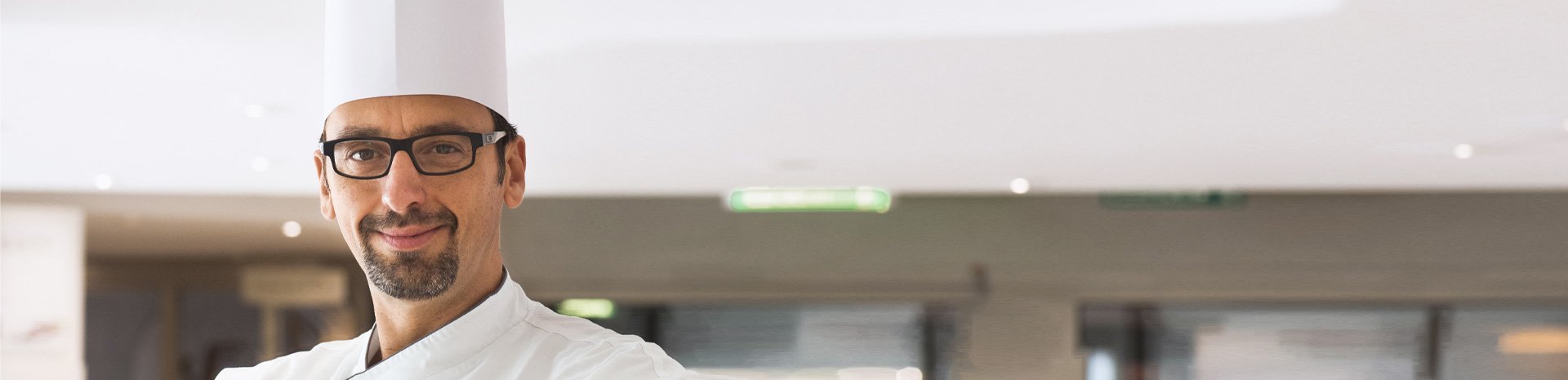 A chef in a white uniform and tall hat in a modern cruise ship dining area | MSC Cruises A chef in a white uniform and tall hat in a modern cruise ship dining area | MSC Cruises
