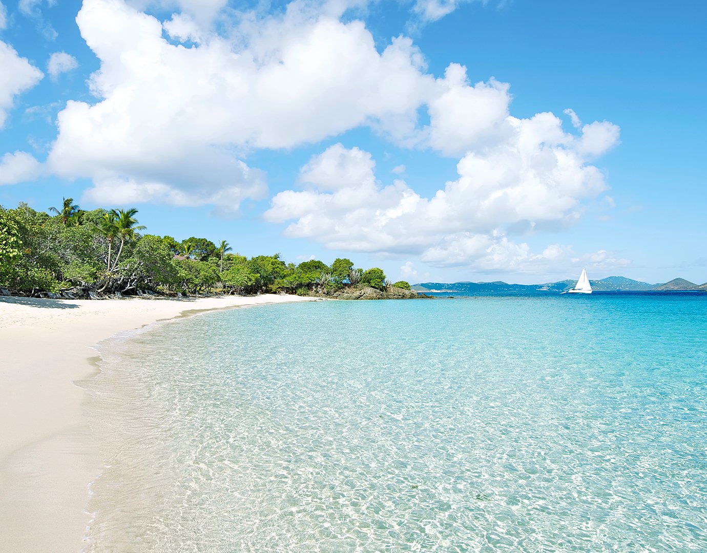 A pristine tropical beach with turquoise water and a sailboat in the distance | MSC Cruises A pristine tropical beach with turquoise water and a sailboat in the distance | MSC Cruises