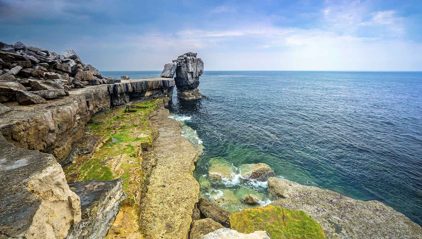Rocky coastal cliffs and clear ocean waters under a blue sky | MSC Cruises Rocky coastal cliffs and clear ocean waters under a blue sky | MSC Cruises