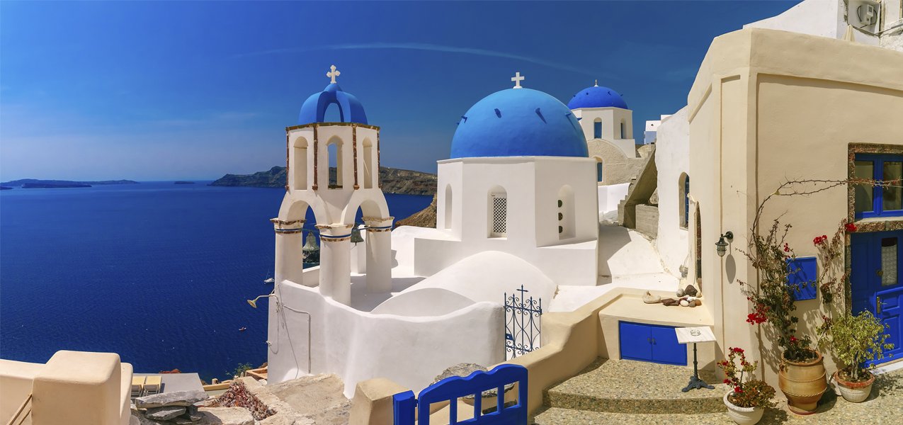 Whitewashed buildings with blue domes overlooking the Aegean Sea in Santorini | MSC Cruises Whitewashed buildings with blue domes overlooking the Aegean Sea in Santorini | MSC Cruises