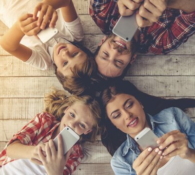Group of friends using smartphones on a wooden deck | MSC Cruises Group of friends using smartphones on a wooden deck | MSC Cruises