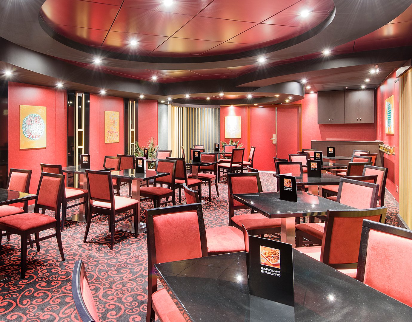 Elegant onboard dining area with red decor and modern seating | MSC Cruises Elegant onboard dining area with red decor and modern seating | MSC Cruises