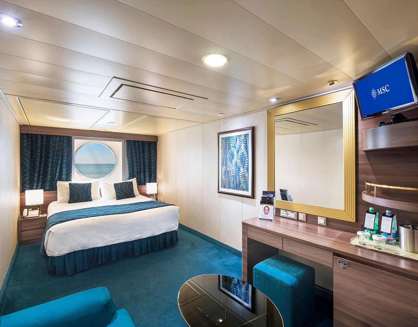 Spacious cruise ship cabin with a large bed, ocean view porthole, and elegant furnishings | MSC Cruises Spacious cruise ship cabin with a large bed, ocean view porthole, and elegant furnishings | MSC Cruises